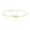 Gold bracelet with three pearl-like stones on a white background