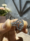 Silver ring with gemstones held in a hand against a blurred background