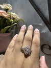 Hand wearing a diamond ring with flowers in the background