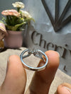 Silver ring held between fingers with a decorative background