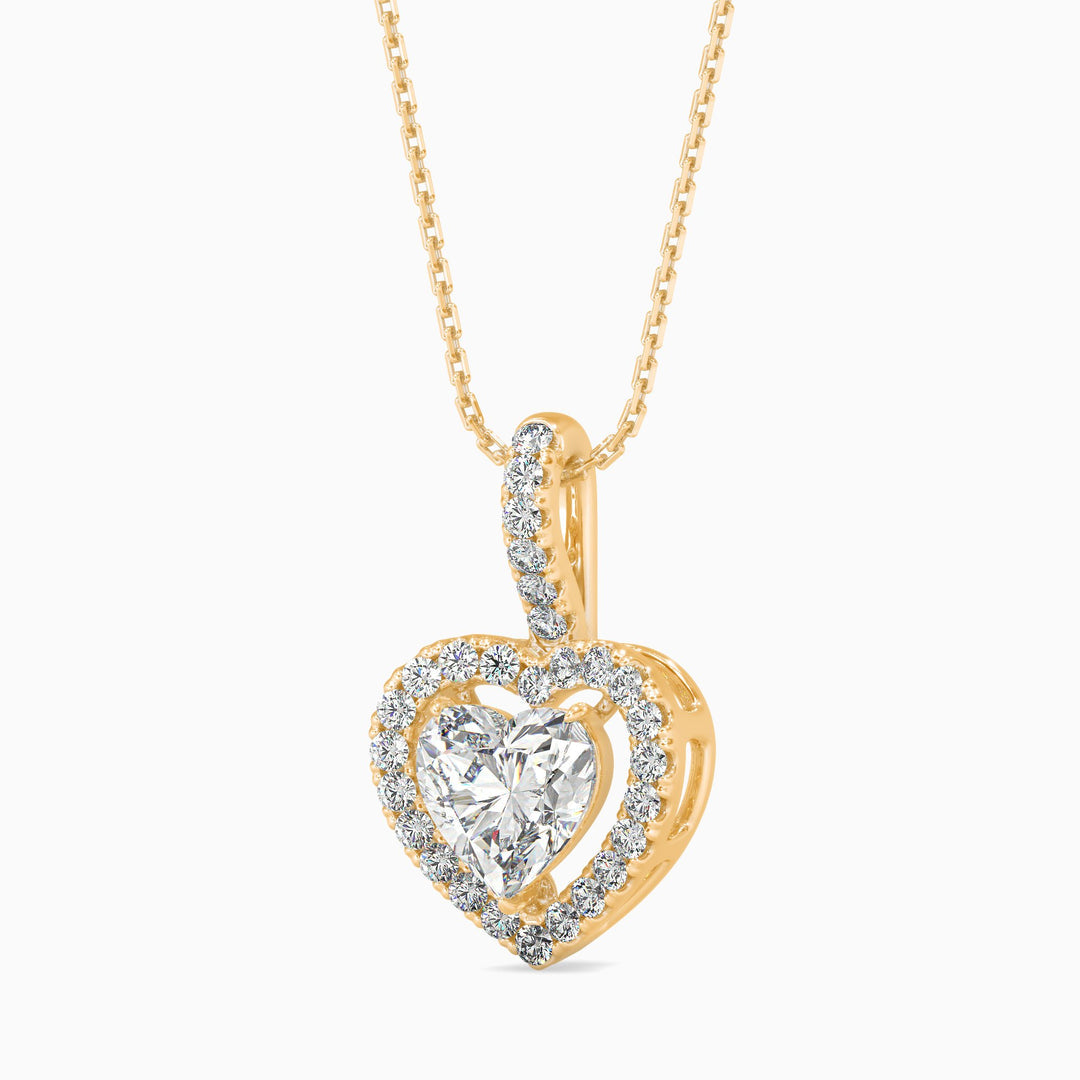 Heart-shaped diamond pendant on a gold chain against a white background