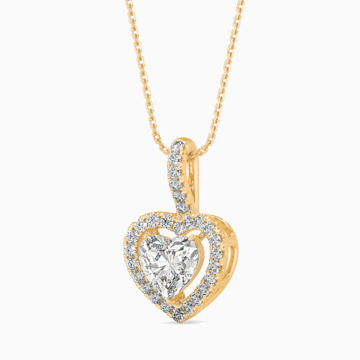 Heart-shaped diamond pendant on a gold chain against a white background