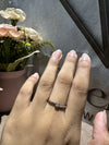 Hand wearing a ring with flowers and a black frame in the background