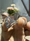 Silver ring with gemstones held by a hand against a blurred background