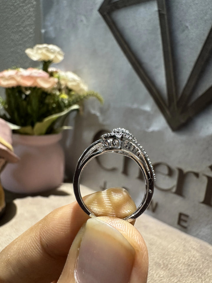 Silver ring held by a hand with a decorative background