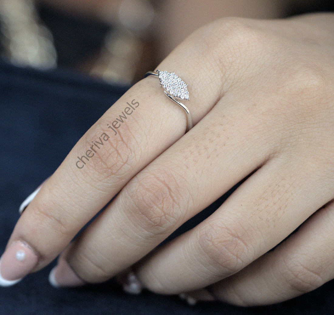 A close-up image of a woman's hand showcasing a ring with a round-cut diamond on her finger.