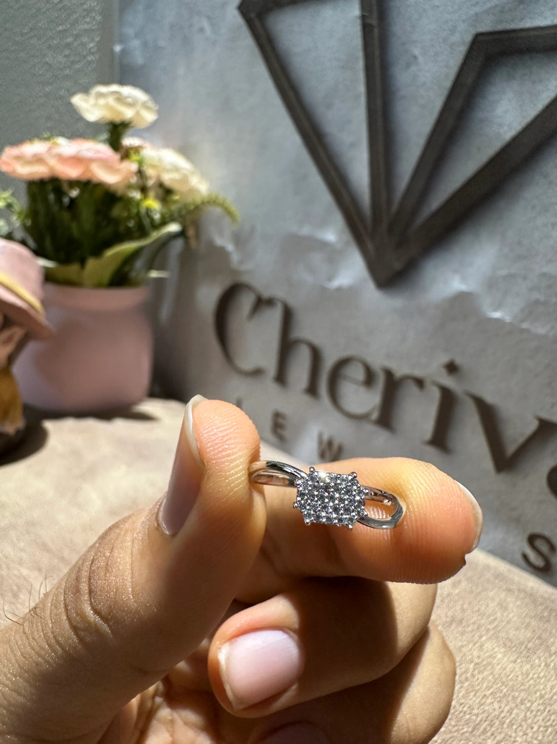 Hand holding a silver ring with a diamond-like center, blurred background 